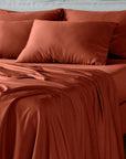 bambaw cozy terracotta bed sheets and pillows on a bed with a neutral background