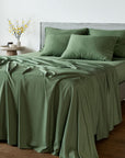 Bambaw Cozy bamboo flat sheet, fitted sheet and pillowcases in olive green colour on a bed in a bright room