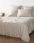 Bambaw Cozy bamboo flat sheet, fitted sheet and pillowcases in sand beige colour on a bed in a bright room