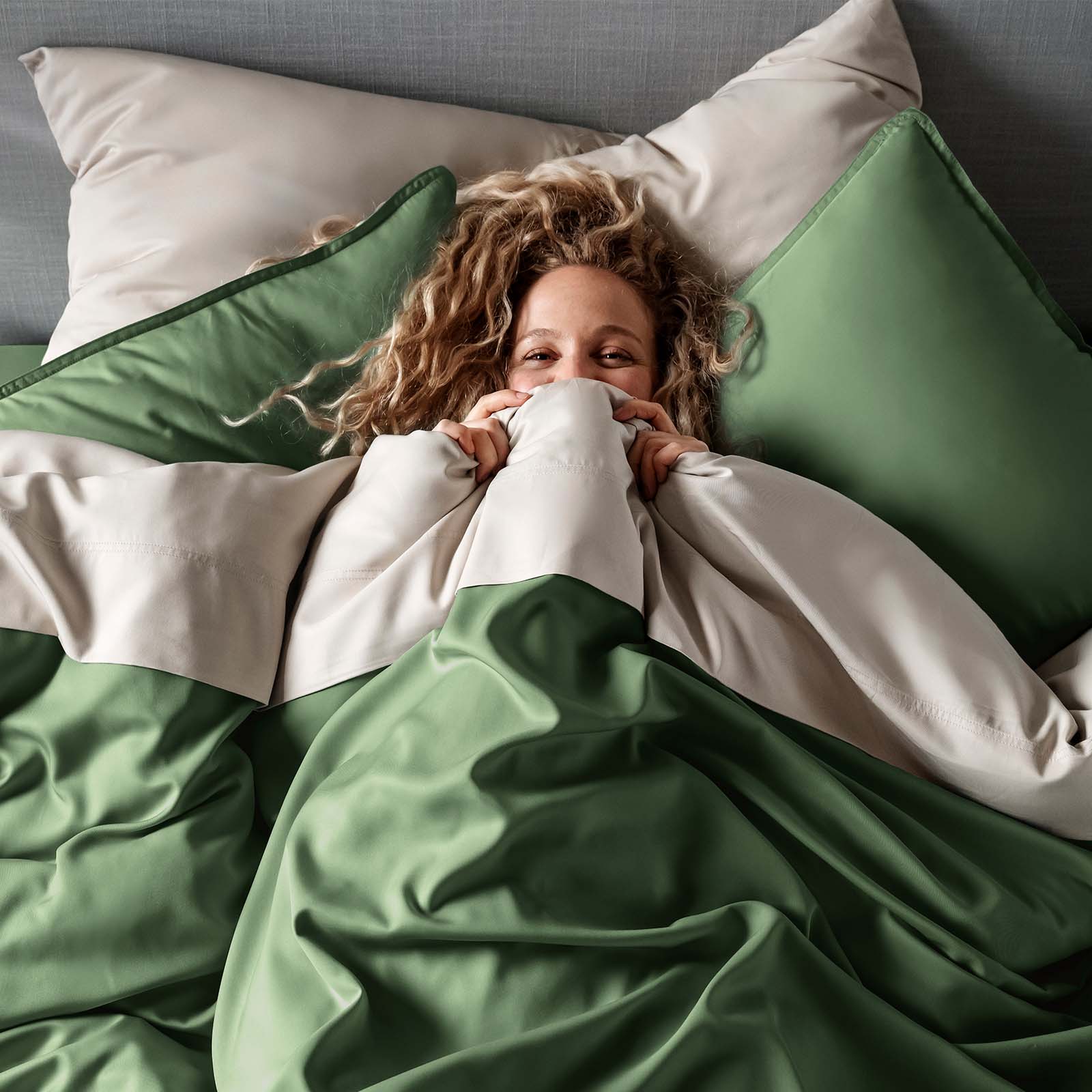 Woman lying in bed with green and white bedding