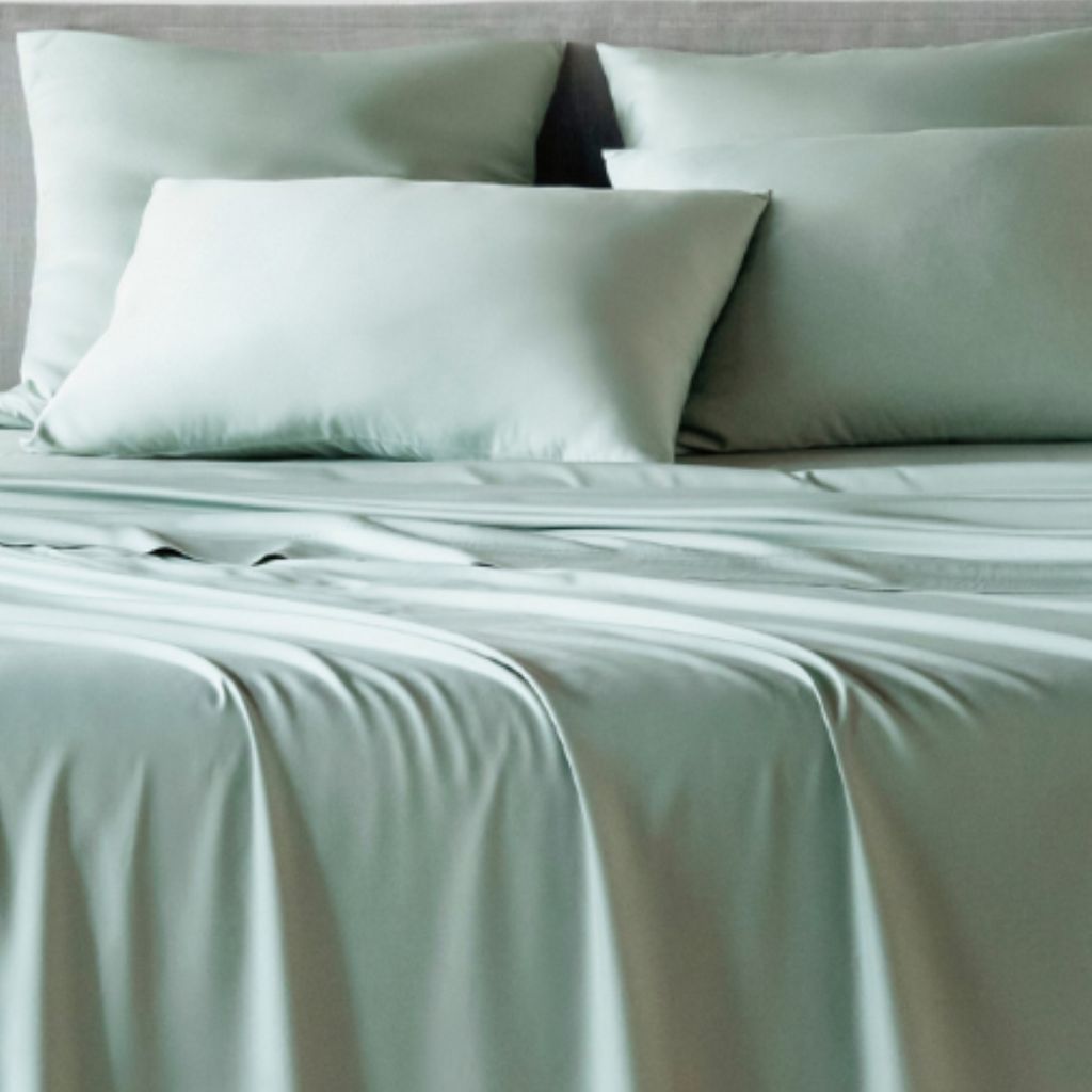 Set of light green bedding including a fitted sheet, two pillows, and a comforter.