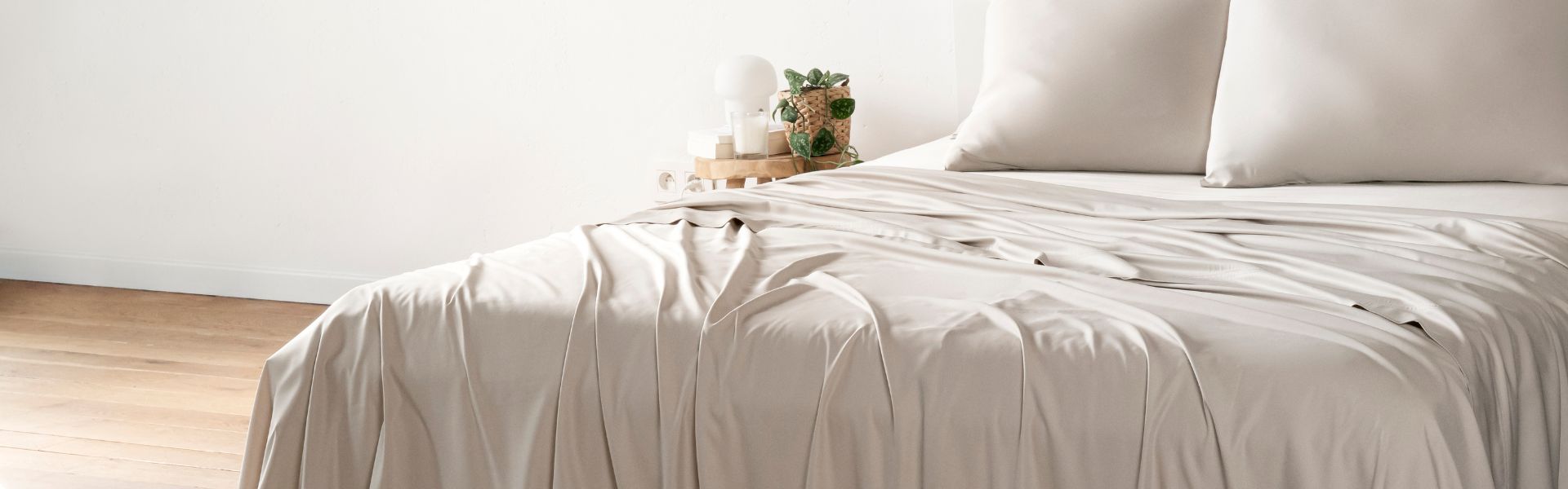 Neatly made bed with Bambaw Cozy sand bed sheets in a minimalistic bedroom.