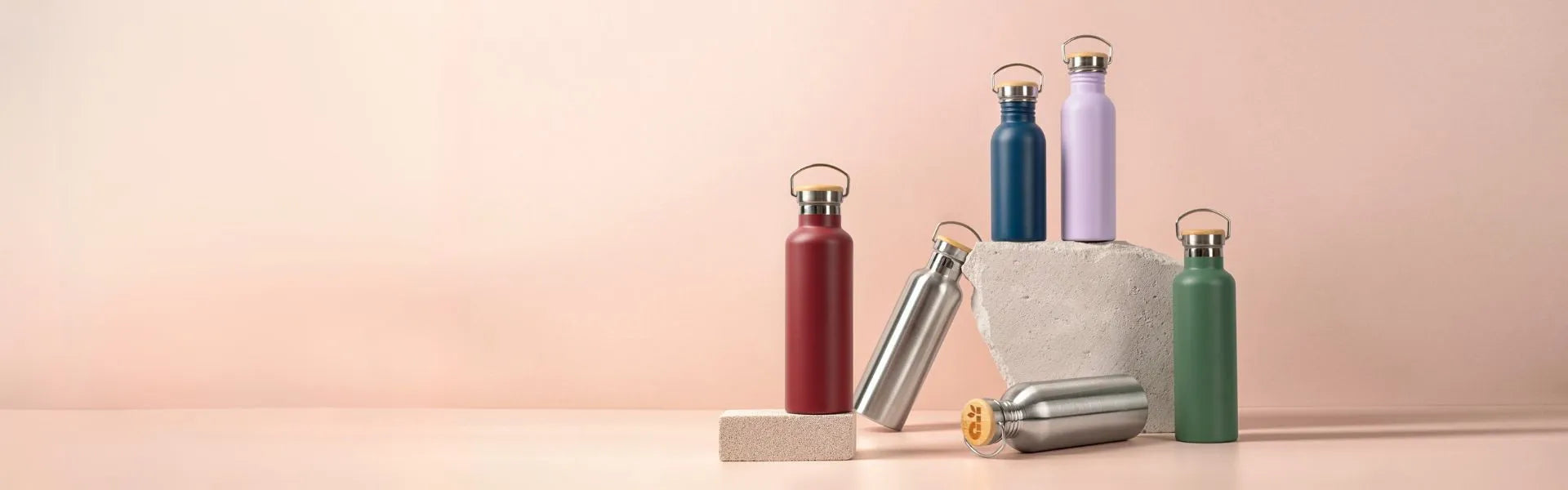 Set of colorful stainless steel water bottles on a light pink background